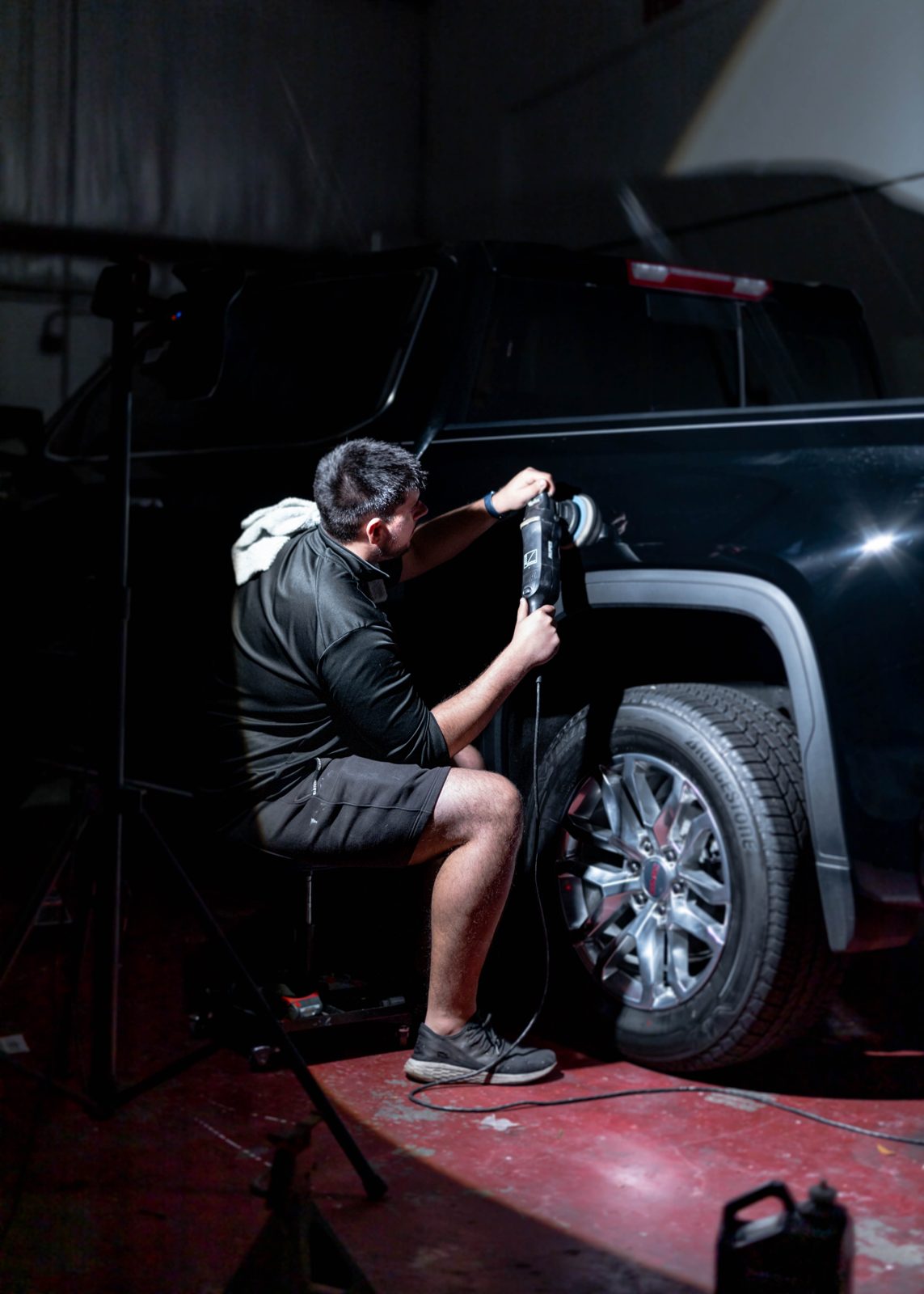 Obsidian detailer buffing a black truck for paint correction at a Chapel Hill home